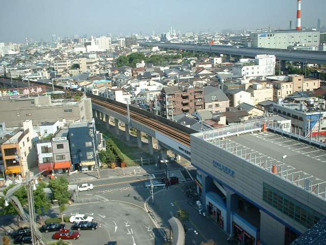 阪神「出屋敷」駅の周辺遠景。店舗やビル、事務所が並ぶにぎわいのある街並み。