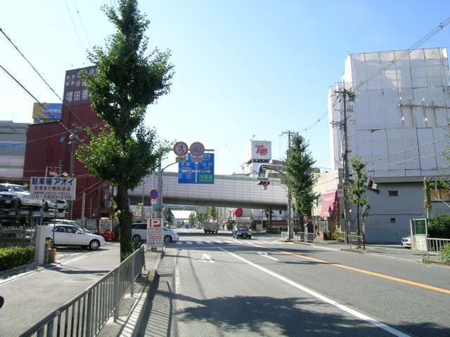 阪神高速の高架の向こう側は、大阪空港への入り口です。道路沿いには店舗が多く建ち並んでいます。