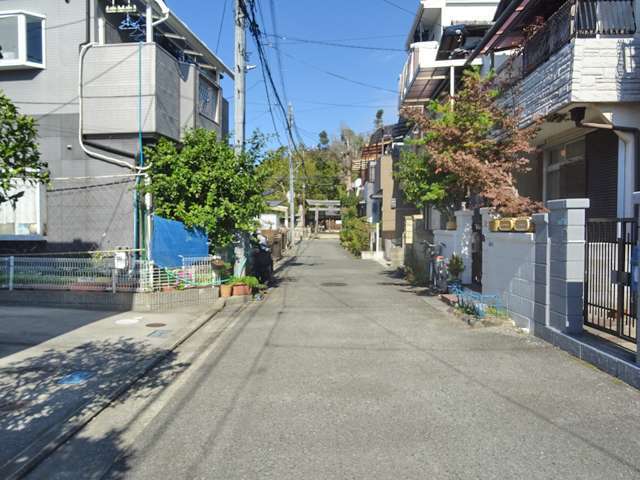町の北部を南方向から見た景色。狭い街路沿いに一戸建てが並んでいます。奥には『三輪神社』があります。