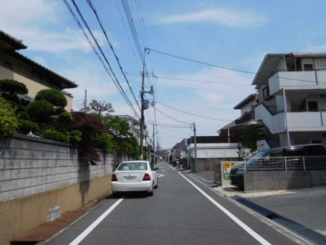 町の南西部を西方向から見た景色。直線的な道路沿いに一戸建てやマンションが混在しています。
