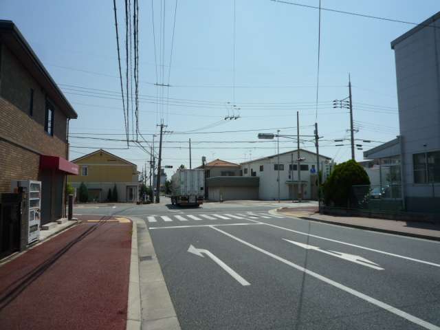 町で最も大きな交差点を北方向から見た景色。一戸建てや店舗などが並んでいます。