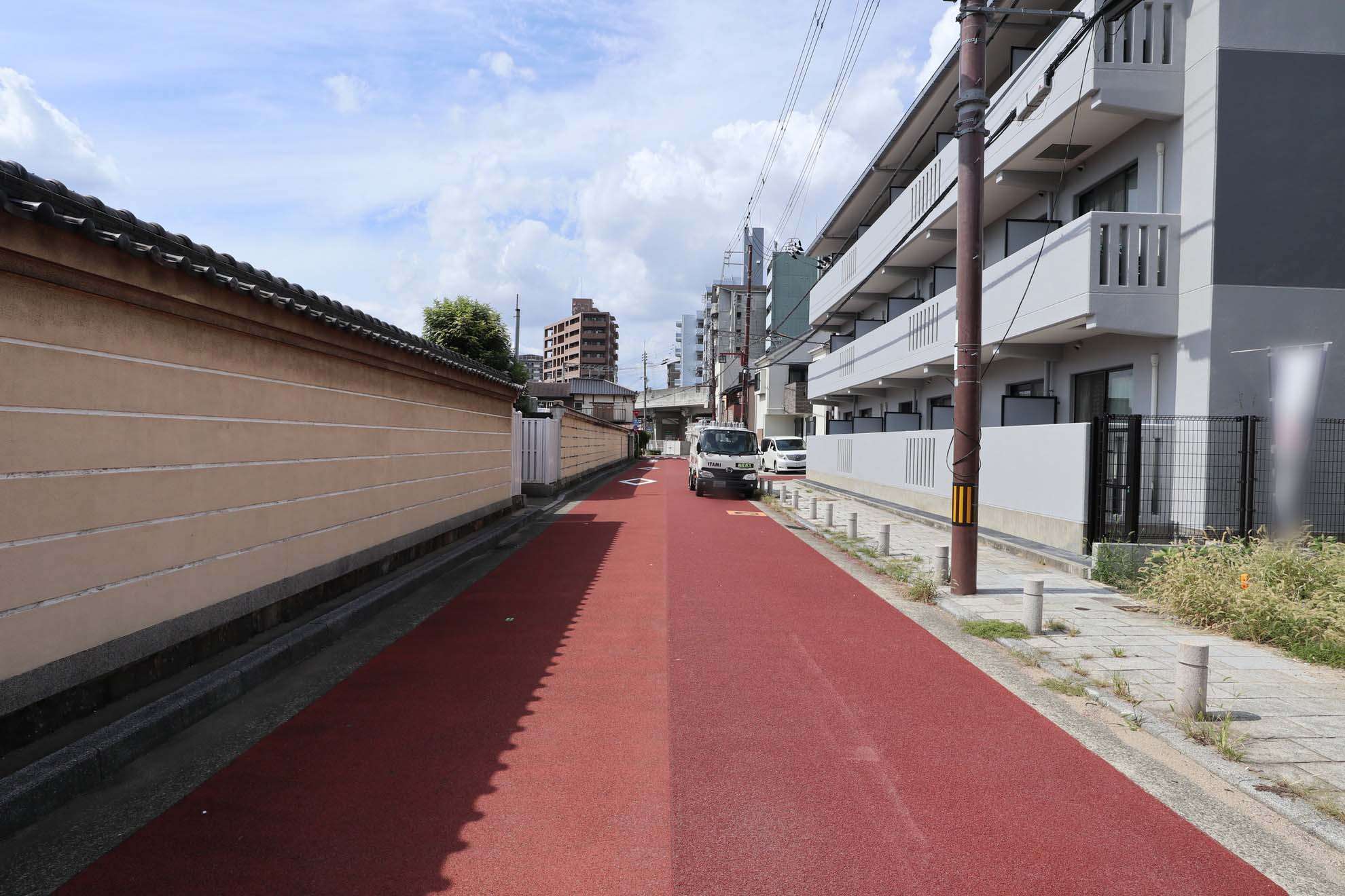 小規模なマンションやハイツ、一戸建て、店舗などが混在する町。写真左手は、『長遠寺』の周囲を囲む塀です。