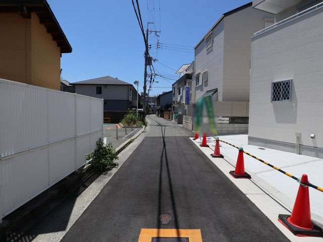 小さな商店や敷地面積10坪前後の一戸建て、アパートが混在する駅前の街並み。