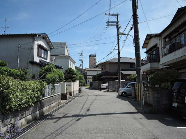 やや狭い街路沿いに一戸建てやマンションが建っています。