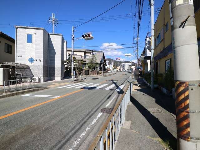 町を南北に通る主要道路。一戸建てが中心で、奥には山々が見えます。