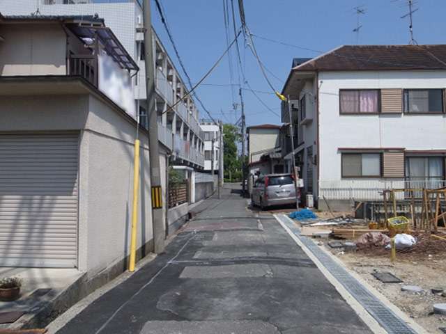 町の西部を西方向から見た景色。狭い街路沿いに一戸建てやマンションなどが混在しています。