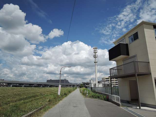 町の西部を南方向から見た景色。堤防の左側を猪名川が流れています。