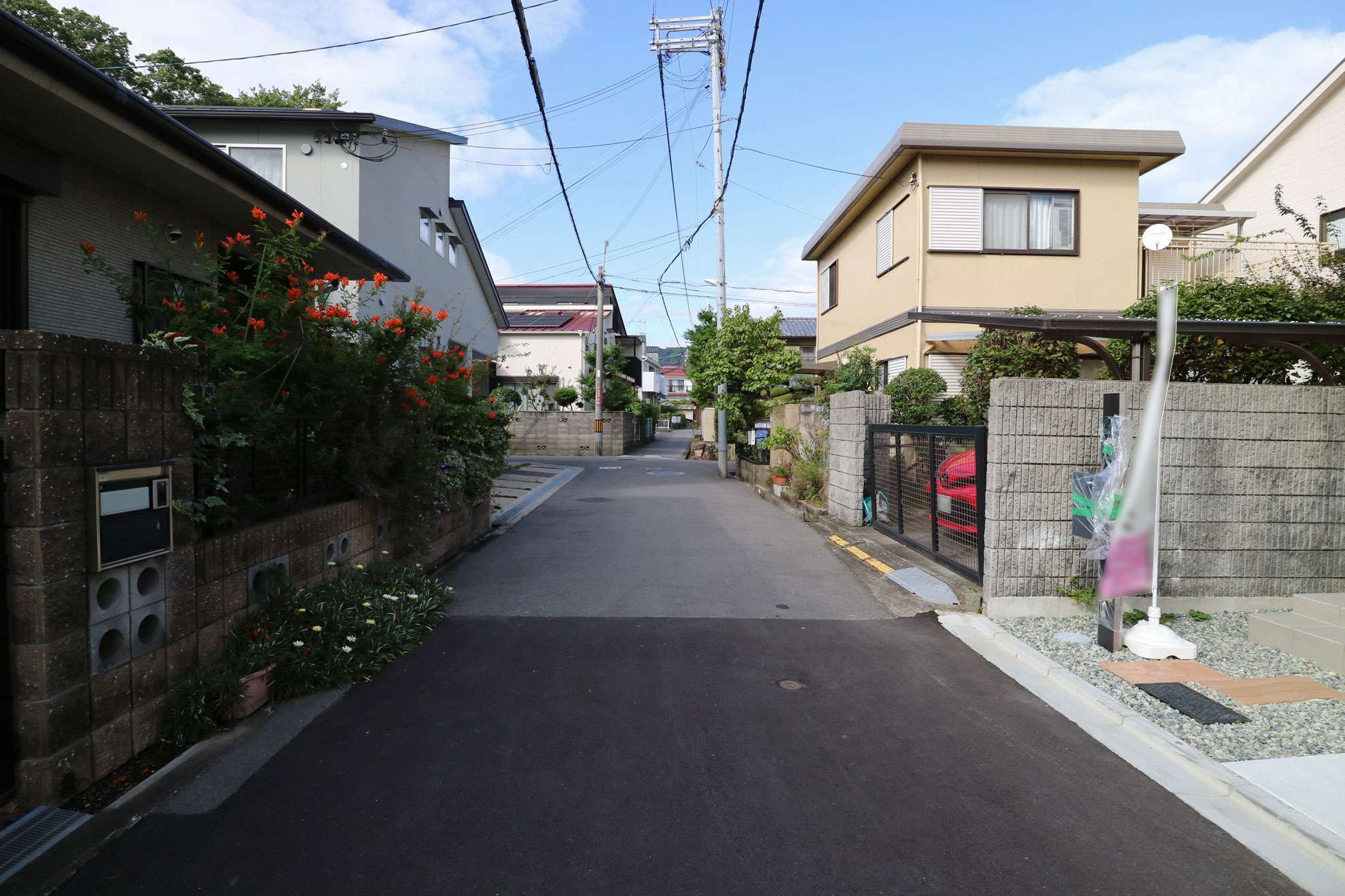 狭い道路沿いに一戸建てなどが並んでいます。