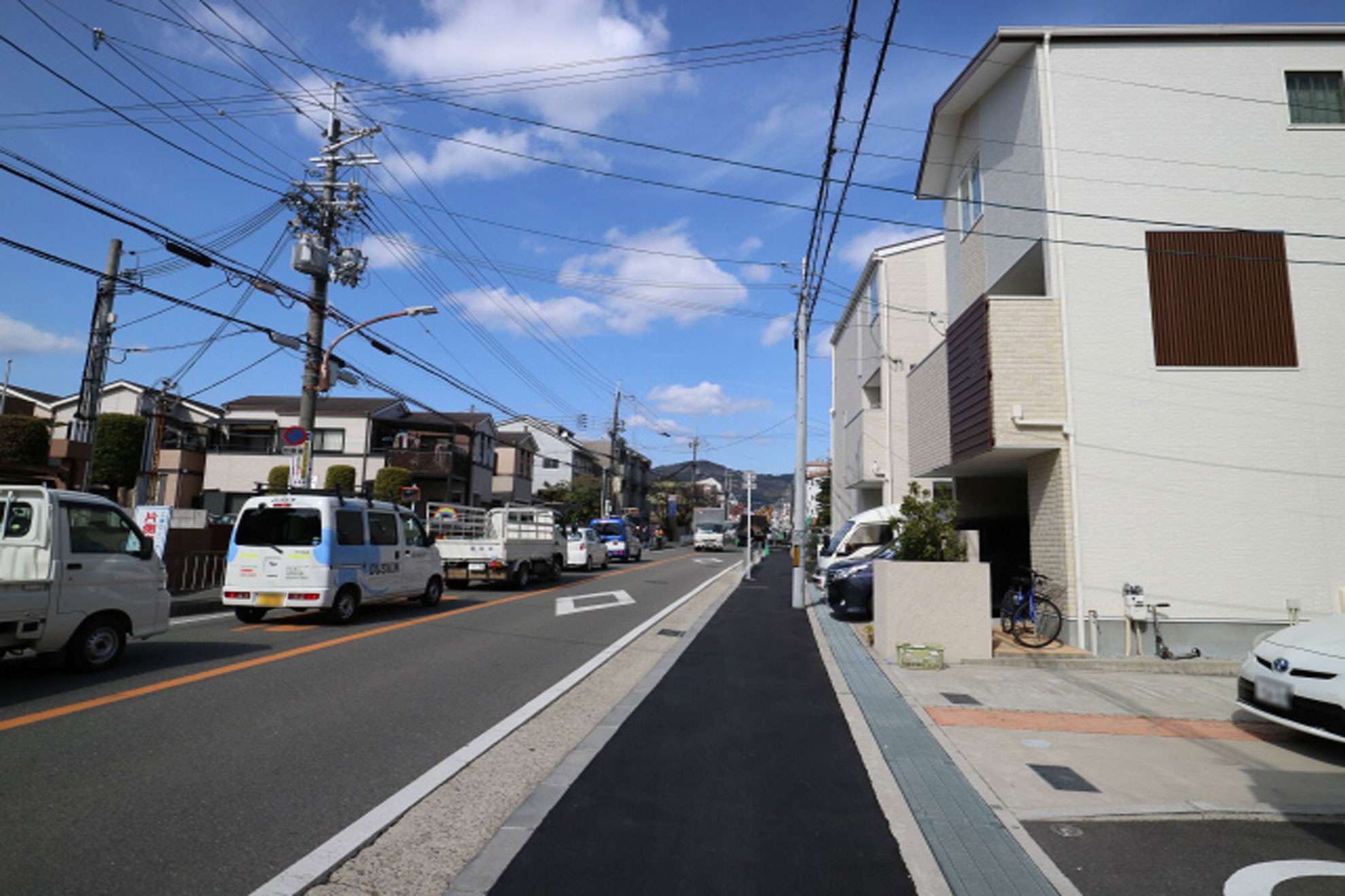 町の西端を通る主要道路。奥には五月山の山々が広がり、そこに向かって緩やかな上り坂が続いています。