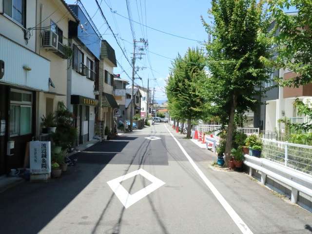 町の中央部を北東方向から見た景色。道路の右側には水路があり、水路沿いに街路樹があります。