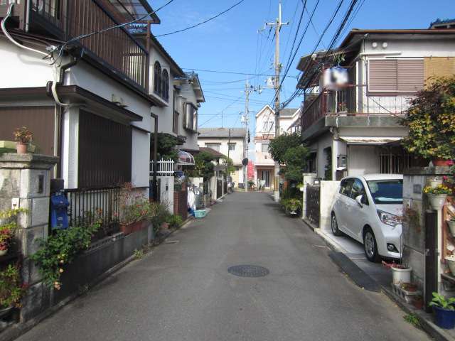 町の中央部を南方向から撮影した景色。生垣や植栽のある家が多く見られます。