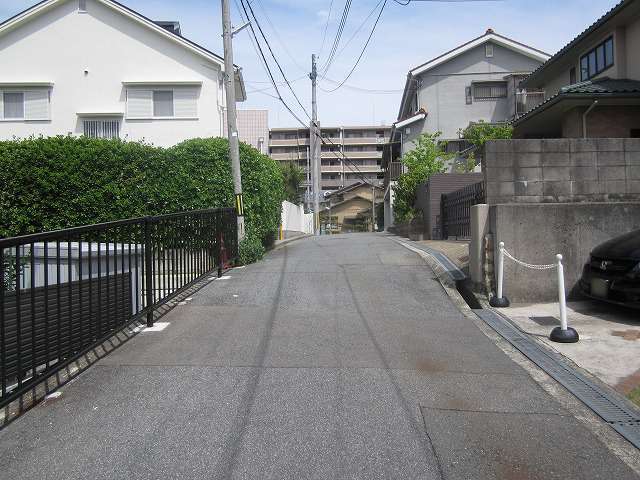 町の中部を西方向から見た景色。道路の両端には一戸建てが並び、奥(東側)にはマンションが建っています。