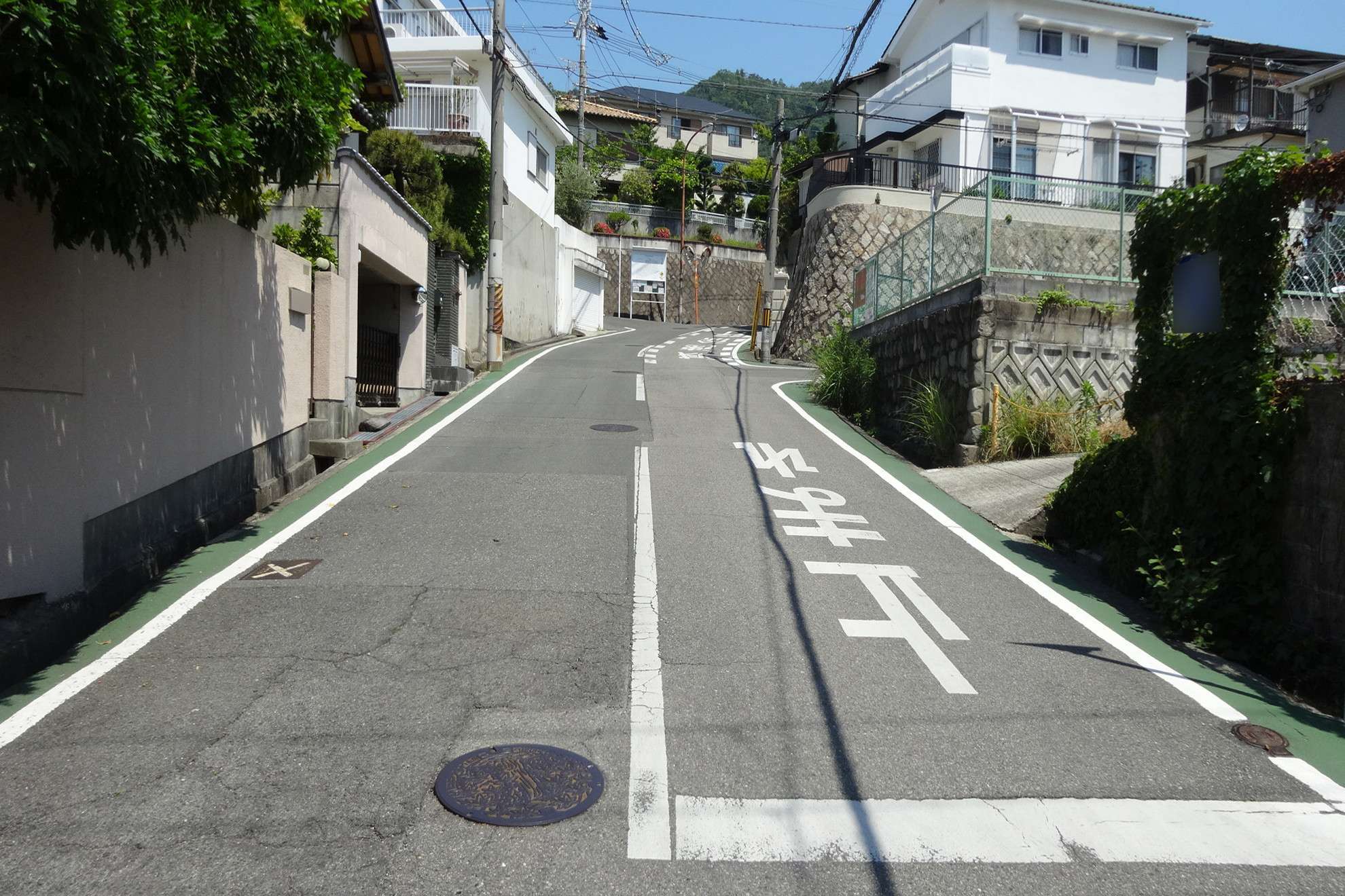 町の南西部を南方向から見た景色。奥に見える山林に向けて急勾配の上り坂が続きます。