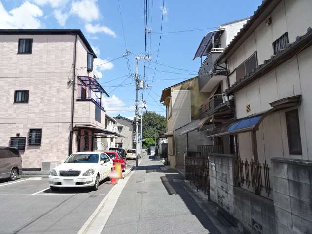 町の北部を西方向から見た景色。狭い街路沿いに一戸建てやハイツなどが並んでいます。奥には『高須神社』の緑が見えます。