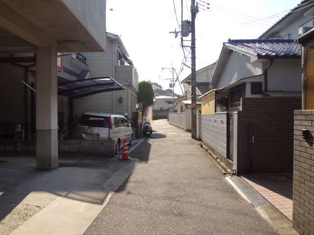 町の北東部にある住宅地を北方向から見た景色。道路の西(右)側にある家は塀で囲まれています。