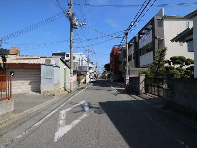 町の中央部を東方向から見た景色。直線的な街路沿いに一戸建てやマンションが混在しています。