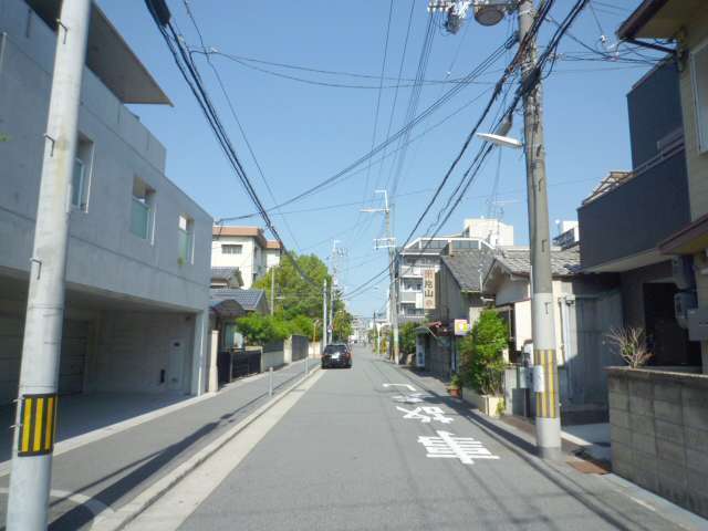 町の西部を南方向から見た景色。直線的な道路沿いに一戸建てやマンションなどが建っています。