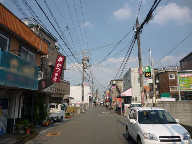 町の西部を西方向から見た景色。一戸建てやハイツ、店舗などが混在しています。