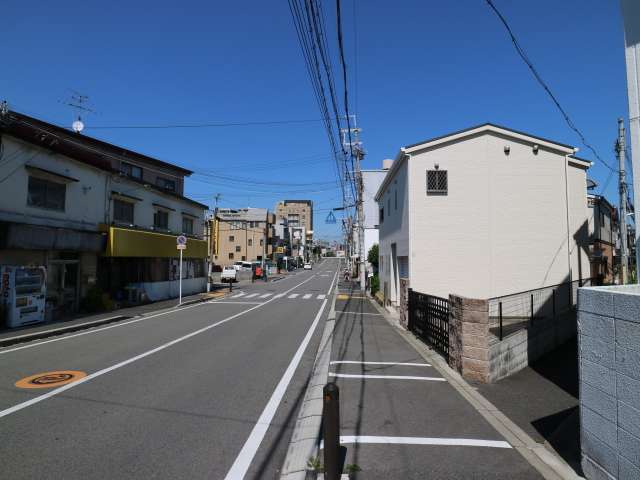 町の北端を通る主要道路。一戸建て以外にも店舗やマンションも混在しています。