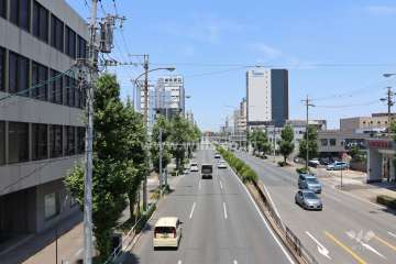 マンション前面道路の遠景。建物は片側三車線の道路沿いにあり交通利便性の高い場所です。