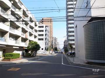 敷地南側の前面道路。周辺は住宅の他、店舗や事務所も多く立ち並んでいます。