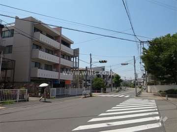 敷地北東側の前面道路（バス通り）。周辺は一戸建てが中心に立ち並ぶ緑豊かな住宅地です。