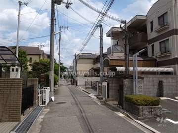 敷地北側の前面道路。周辺は区画の整ったマンションと一戸建てが混在する静かな住宅地です。