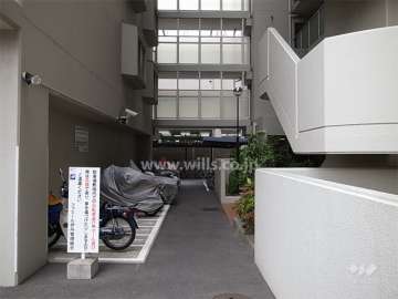 バイク置き場と駐輪場。奥上部は、棟を結ぶ渡り廊下。
