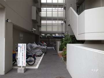 バイク置き場と駐輪場。奥上部は、棟を結ぶ渡り廊下。