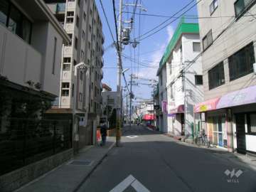 敷地東側の前面道路。周辺は駅前の商業地です。