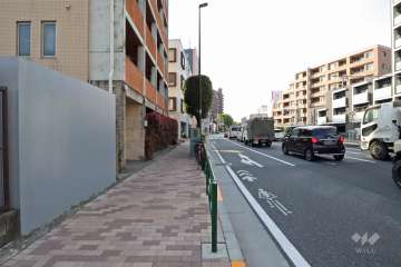 敷地北側の前面道路は環七通りです（東側から）。バス停がマンション目の前にあります。