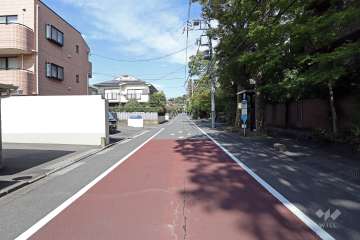 敷地西側の前面道路は大蔵通りです（南西側から）。バス停が目の前にあります。