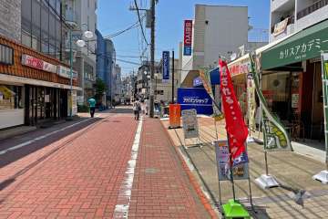 敷地の南側前面道路にはスーパーやコンビニ、飲食店など多数の店舗が並んでいます（東側から）。