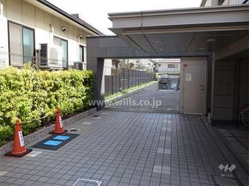 リングシャッター付きの駐車場入り口。エントランスの庇が長く、手前側は車寄せになっています。