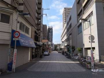 敷地北側の前面道路。向かい側は駅前の商業施設です。