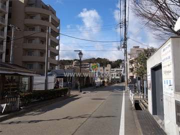 北側の前面道路の交通量は多め。周辺には住宅の他、店舗が多く建ち並んでいます。