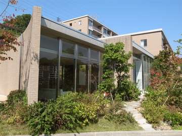 植栽に囲まれたガラス張りのエントランス棟