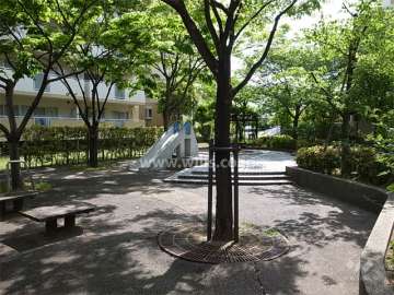 緑豊かで、遊具やベンチが設置された敷地内の広場