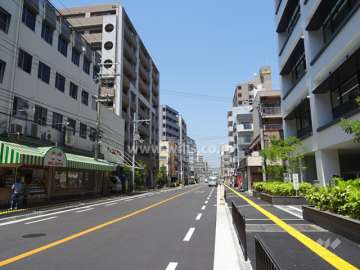 敷地東側の前面道路。商業地域内にあり、マンションの他に、店舗やテナントビルが混在します。