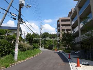 緩やかな南斜面地に立地し、西側は道を挟んで一戸建てが立ち並ぶ住宅地です。
