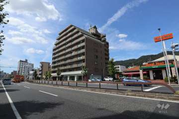 本山グランドハイツの遠景。国道2号沿いにあり、周辺にはレストランやスーパーなどの商業施設があります。