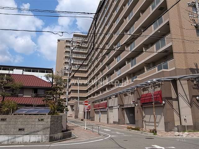 敷地西側の前面道路。低層階には店舗が入っています。