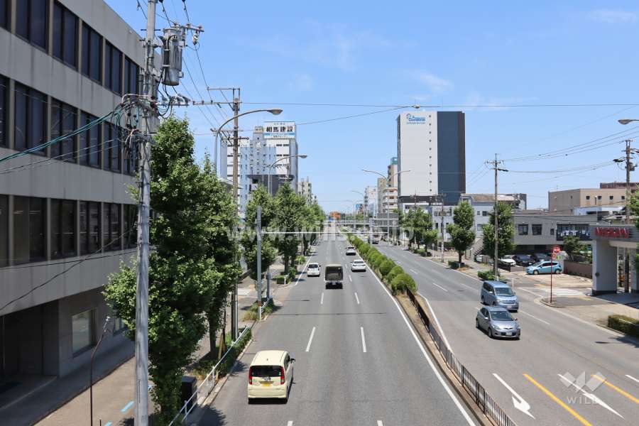 マンション前面道路の遠景。建物は片側三車線の道路沿いにあり交通利便性の高い場所です。