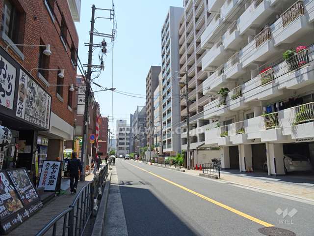 敷地東側の前面道路（北側から）。周辺は、マンションのほか飲食店などの商業施設が建ち並んでいます。
