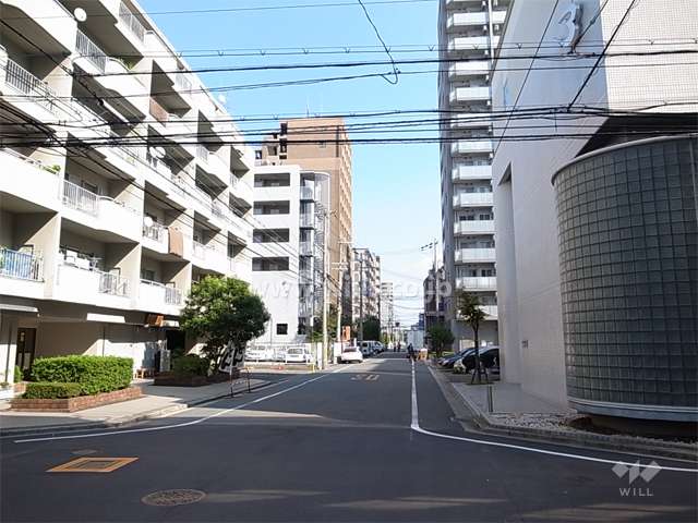 敷地南側の前面道路。周辺は住宅の他、店舗や事務所も多く立ち並んでいます。