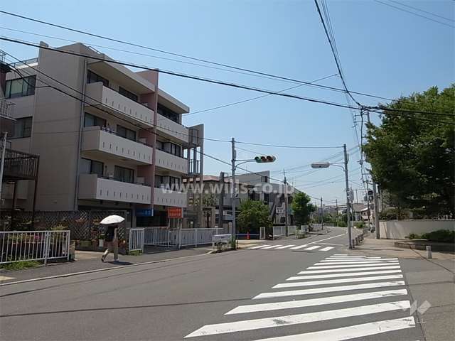 敷地北東側の前面道路（バス通り）。周辺は一戸建てが中心に立ち並ぶ緑豊かな住宅地です。