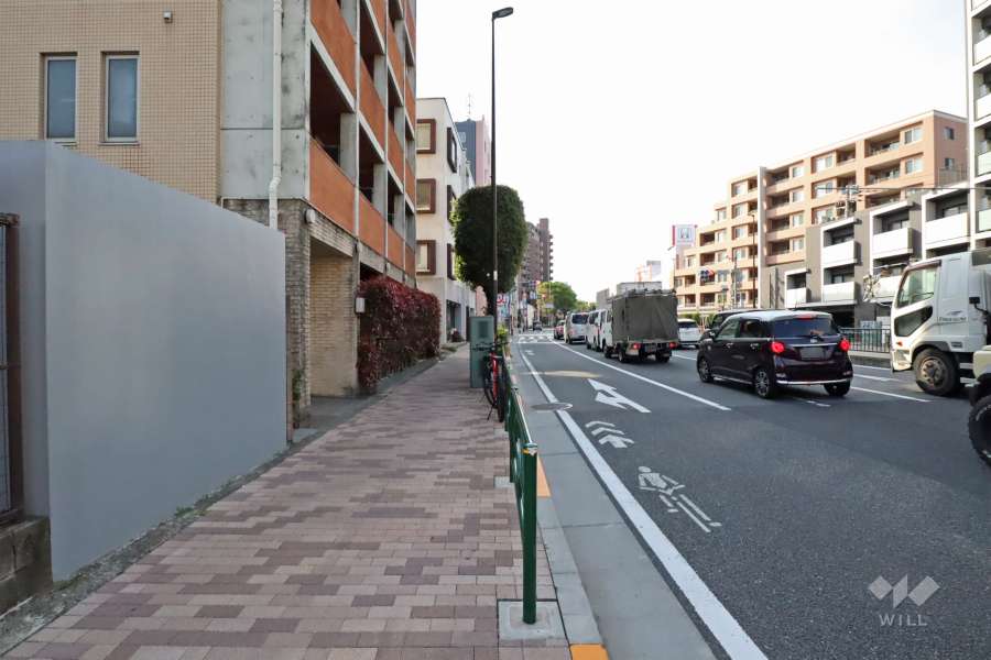敷地北側の前面道路は環七通りです（東側から）。バス停がマンション目の前にあります。