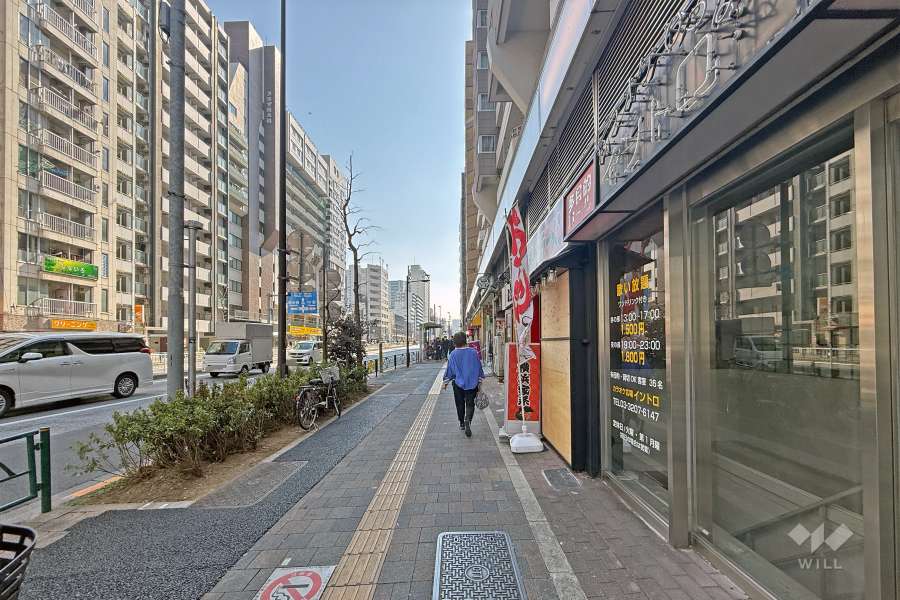 敷地の東側前面道路は都道305号です（北側から）。「大久保通り」バス停がマンションの目の前にあります。