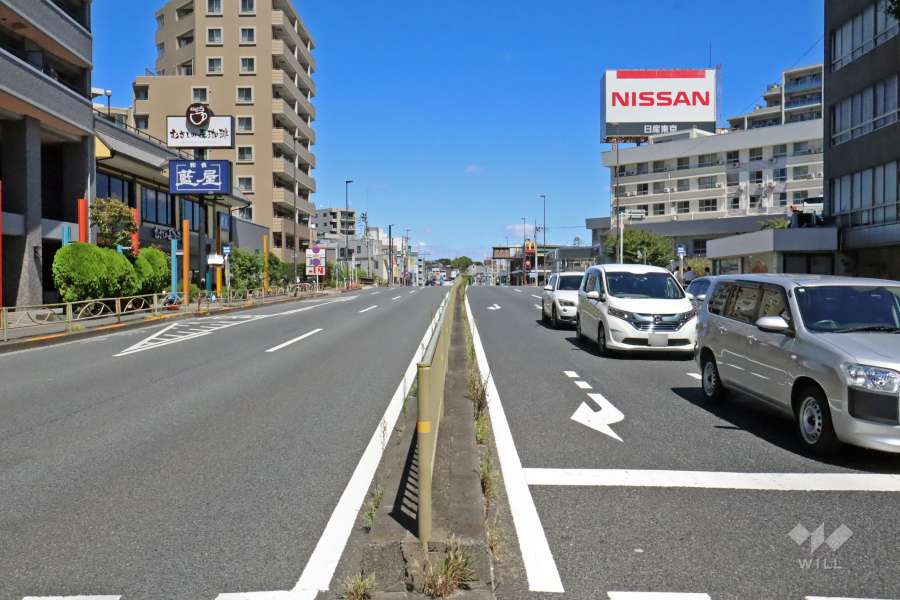 敷地南東側の前面道路は国道1号線です(南西側から)。バス停がマンション目の前にあります。