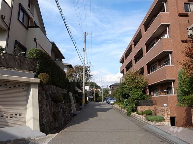 敷地西側の前面道路。小高い丘の上に立地し、周辺には一戸建てが中心に並んでいます。